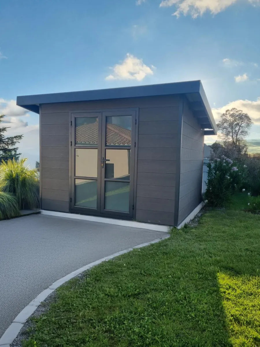 Abri composite gris installé chez un client au bout d'une allée