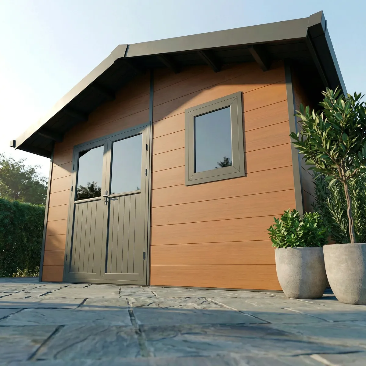 Abri composite Isora 15 m² brun sur une terrasse dallée, plantes en pot