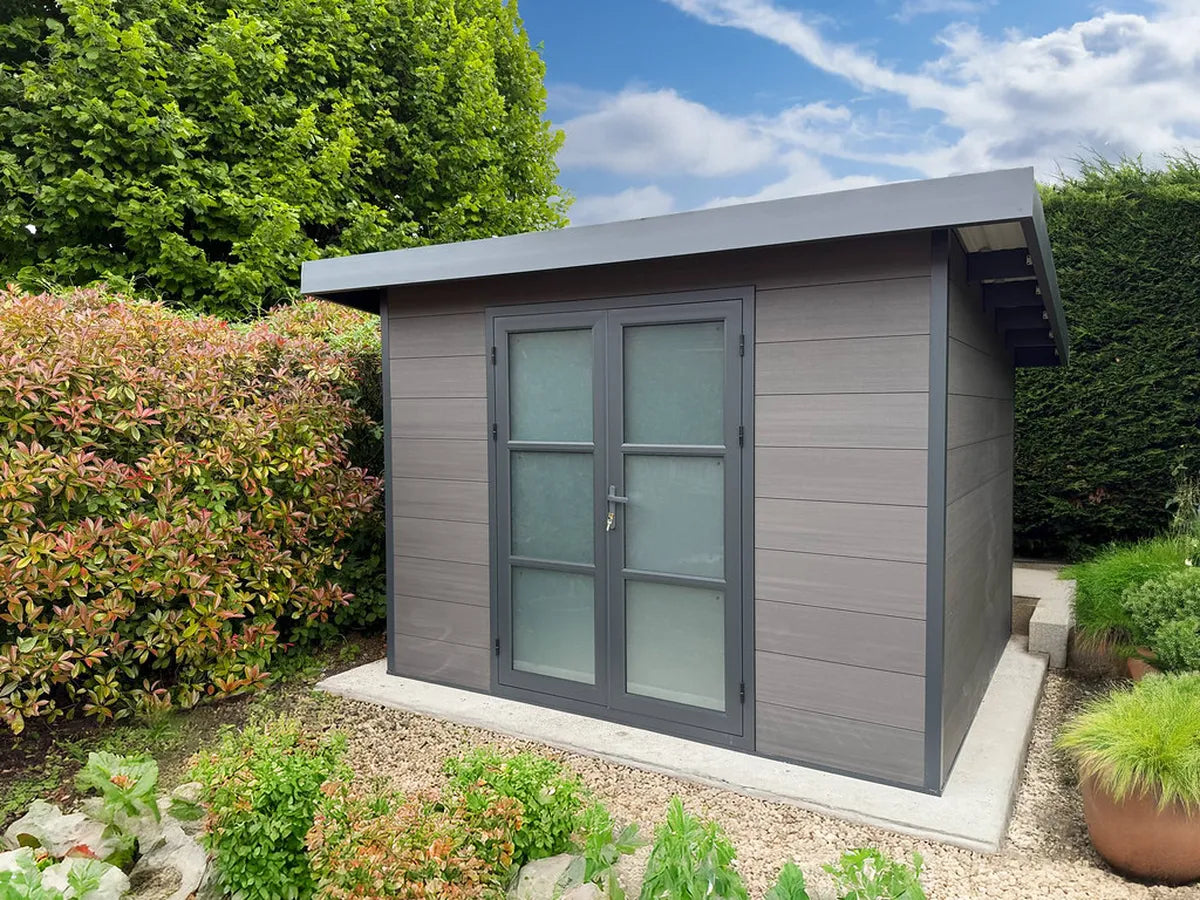 Abri composite gris clair installé chez un client, entouré d'arbustes