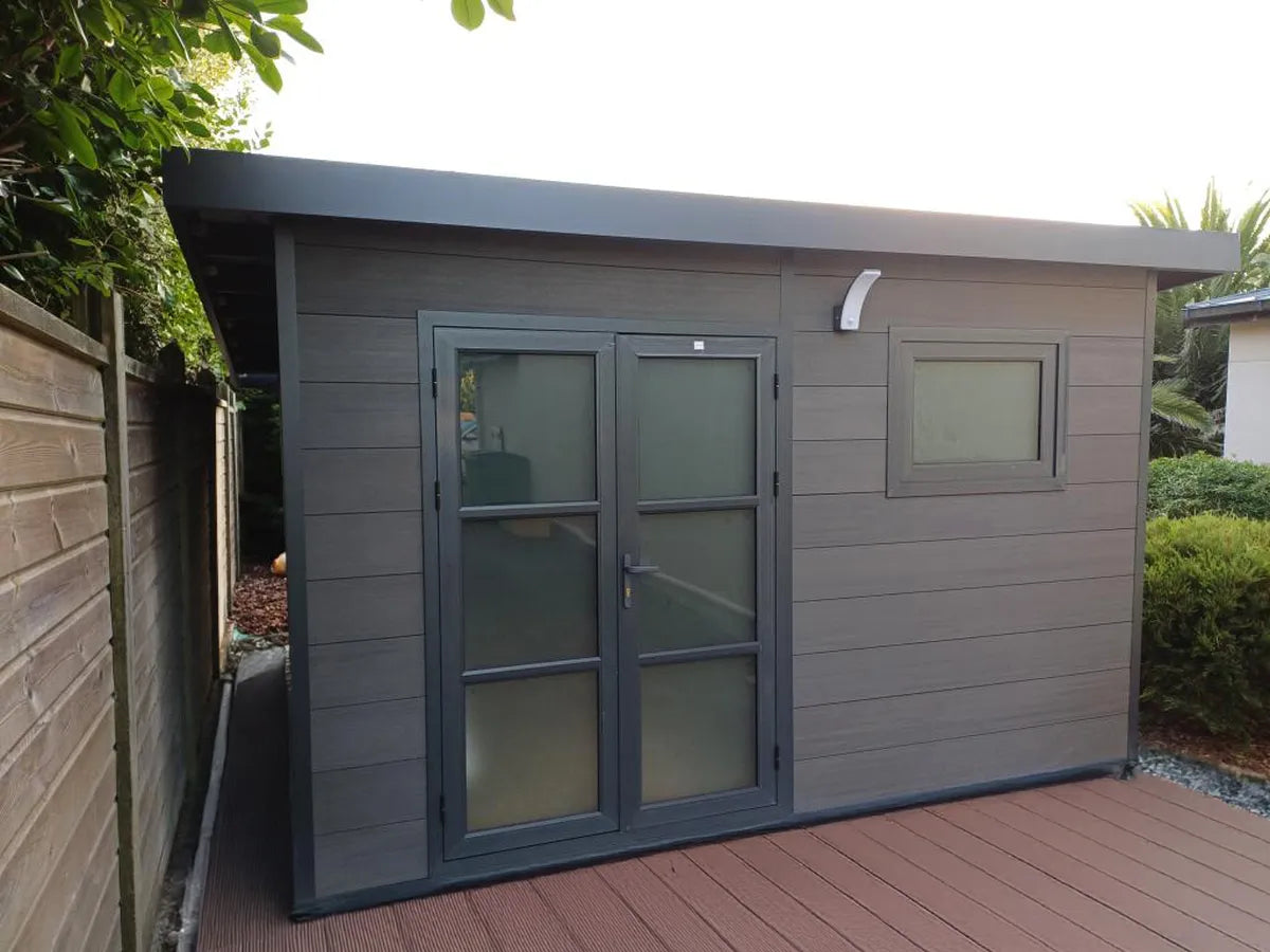 Abri composite gris à porte double et fenêtre sur une terrasse en bois, chez un client