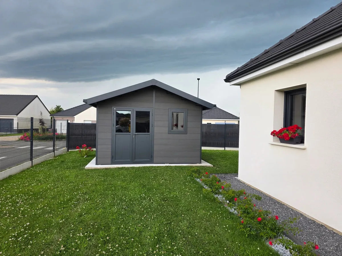 Abri composite Isora gris installé chez un client, le long de la maison